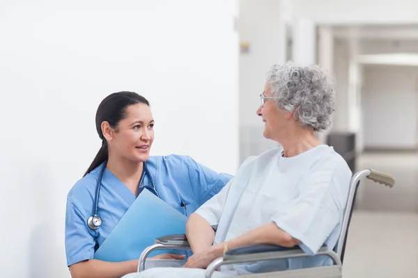 Enfermeira ao lado de um paciente em uma cadeira de rodas — Fotografia de Stock
