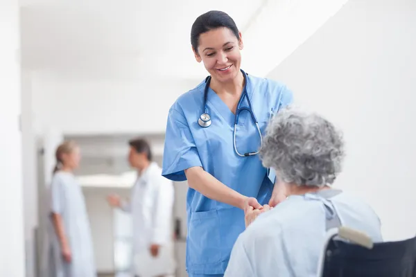 Nurse standing next to a patient while holding her hands — Stock Photo, Image