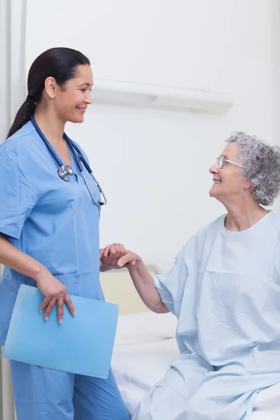 Äldre patienten hålla handen på en sjuksköterska — Stockfoto