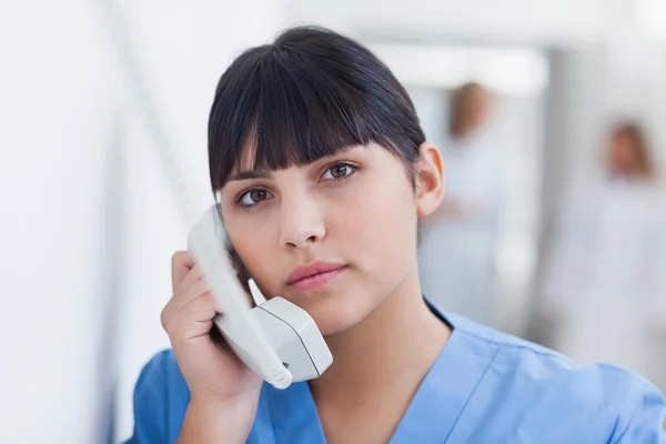 Infermiera con un telefono nel corridoio — Foto Stock