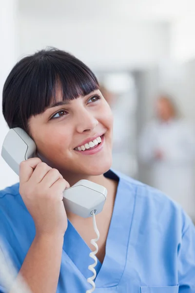 Enfermeira sorridente segurando um telefone — Fotografia de Stock