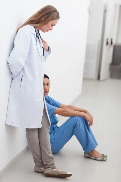 Médico ao lado de uma enfermeira sentada no chão — Fotografia de Stock