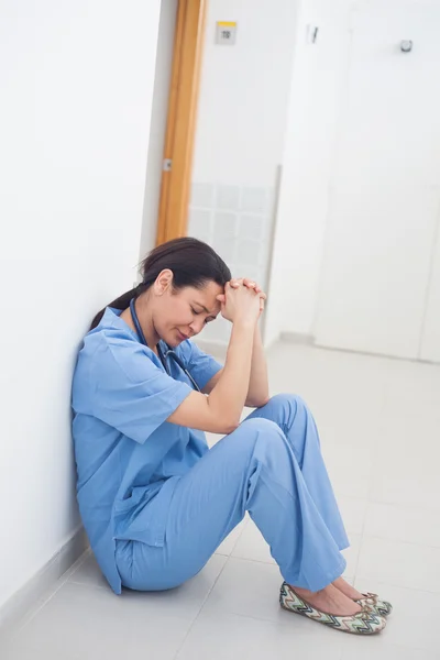 Smutne, pielęgniarka, siedząc na podłodze — Zdjęcie stockowe