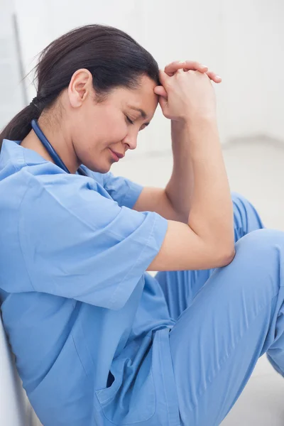 Krankenschwester sitzt mit dem Kopf auf dem Boden — Stockfoto