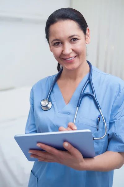 Krankenschwester blickt in Kamera, während sie ein eBook in der Hand hält — Stockfoto