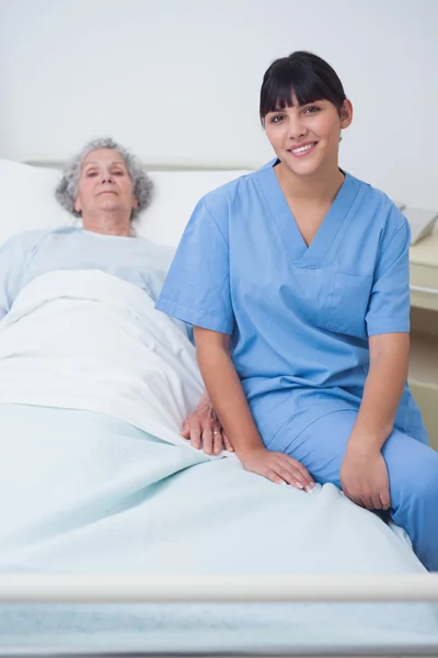 Νοσοκόμα που κάθεται σε ένα ιατρικό κρεβάτι — Φωτογραφία Αρχείου