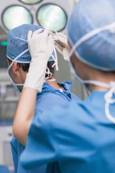 Nahaufnahme einer Krankenschwester, die einem Arzt die Maske bindet — Stockfoto