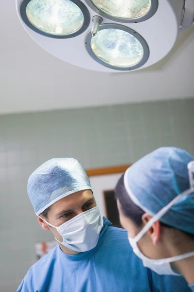 Doctor looking at a nurse below the light — Stock Photo, Image