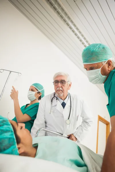 Arts en chirurg kijken naar een vrouwelijke patiënt — Stockfoto