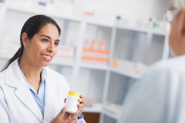 Pharmacien tenant une boîte de médicaments tout en regardant un patient — Photo