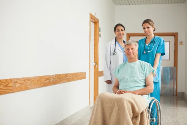 Paciente em cadeira de rodas ao lado de enfermeiras — Fotografia de Stock