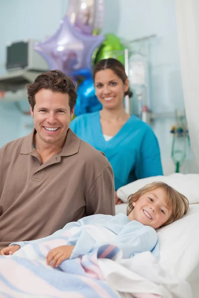 Niño acostado en una cama médica junto a su padre — Foto de Stock