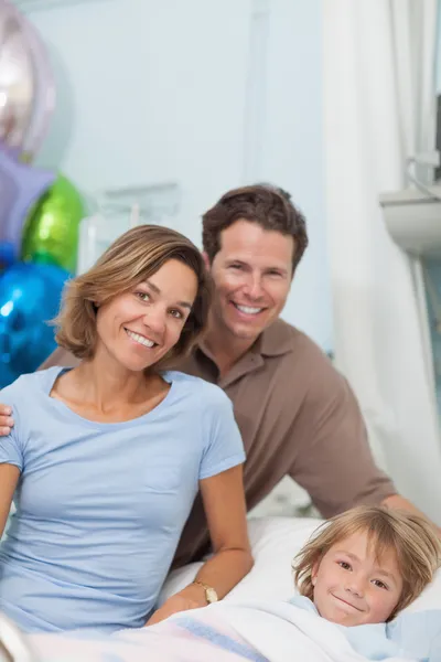 Niño en una cama médica junto a sus padres — Foto de Stock