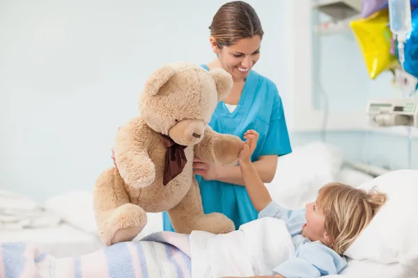 Enfermera mostrando un osito de peluche a un niño — Foto de Stock