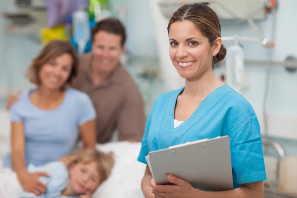 Enfermera sosteniendo un portapapeles al lado de una familia —  Fotos de Stock