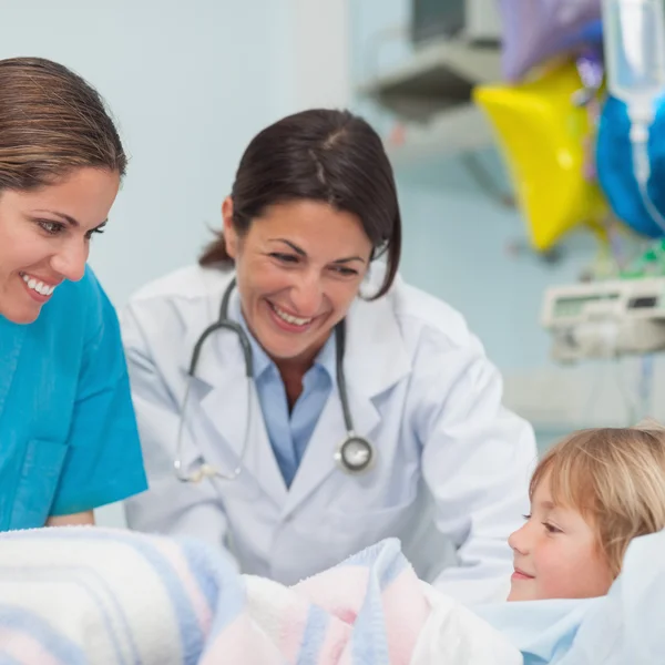 Médico e enfermeira sorrindo para uma criança — Fotografia de Stock
