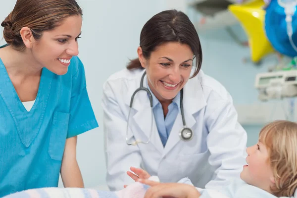 Медсестра и доктор улыбаются ребенку — стоковое фото