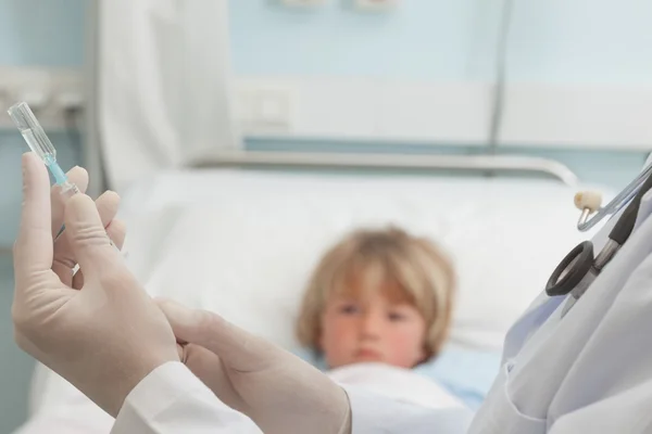 Doctor preparing a syringe in front of a child — Stock Photo, Image