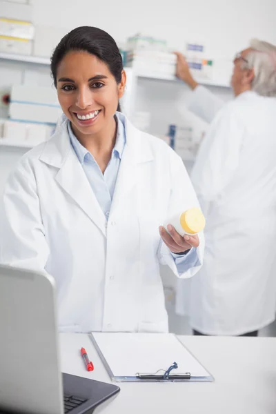 Female pharmacist holding a drug box while smiling — Stock Photo, Image