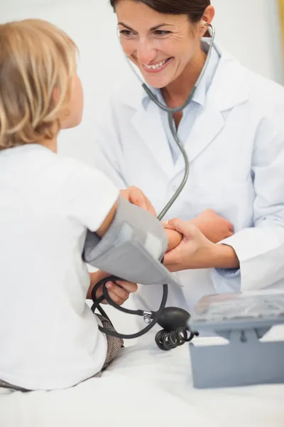 Médico sonriente midiendo la presión arterial de un niño —  Fotos de Stock