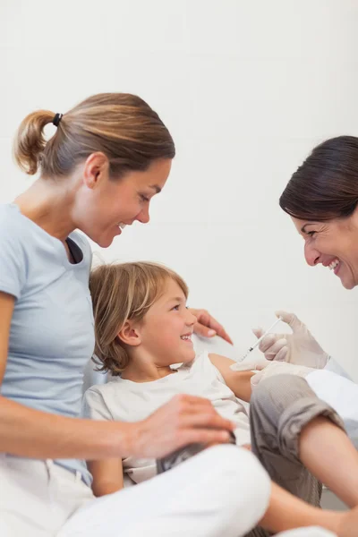 Child sitting on a bed receiving an injection — Stock Photo, Image