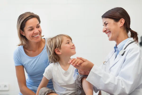 Medico sorridente che ausculta l'avambraccio di un bambino — Foto Stock