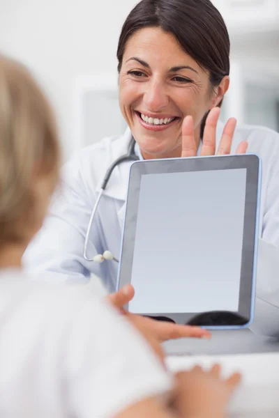 Улыбающийся врач показывает планшетный компьютер ребенку — стоковое фото