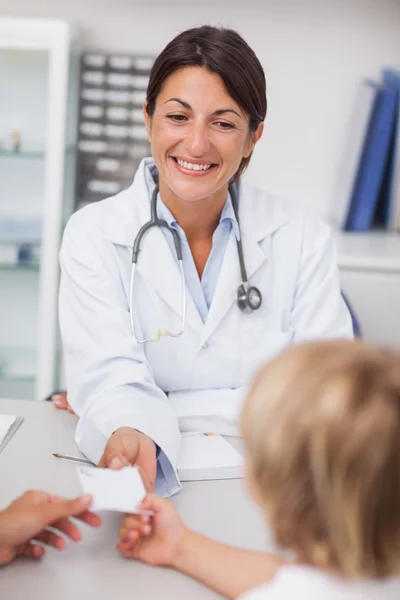 Médico sorridente que dá uma receita a um paciente — Fotografia de Stock