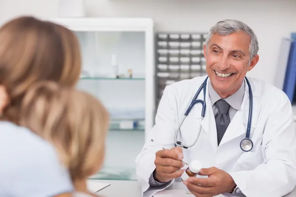 Lächelnder Arzt, der auf eine Medikamentenkiste schreibt — Stockfoto