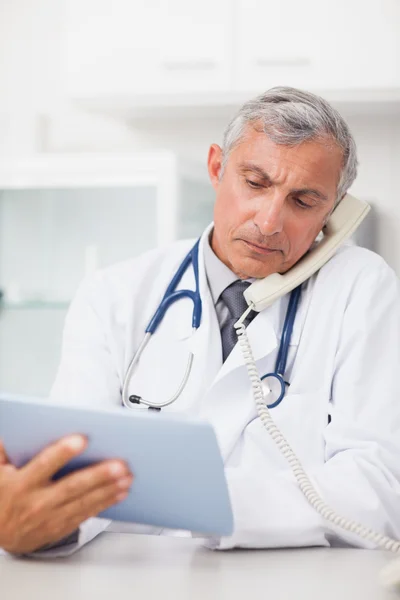 Doctor using a tablet computer while calling — Stock Photo, Image