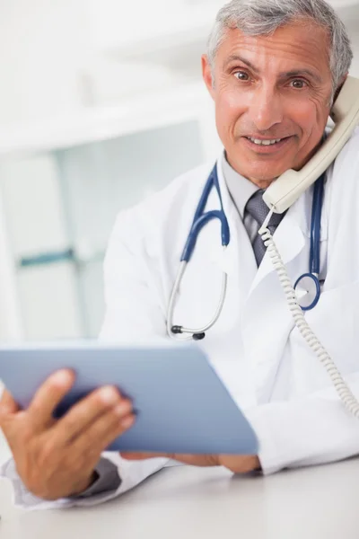 Médico sorridente segurando um computador tablet e chamando — Fotografia de Stock