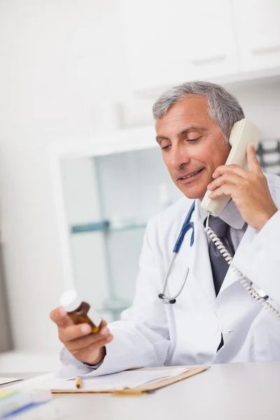 Médico segurando uma caixa de drogas e um telefone — Fotografia de Stock