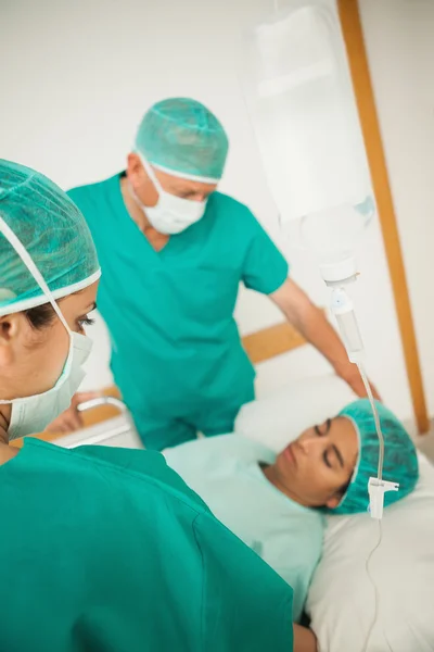 Twee chirurgen kijken naar een onbewuste patiënt — Stockfoto