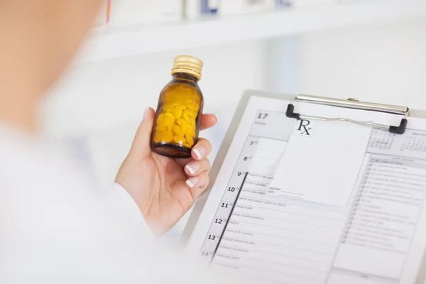 Pharmacist holding a drug bottle and a clipboard — Stock Photo, Image