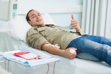 Smiling transfused patient lying on a bed clipart