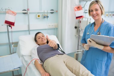 Nurse next to a patient while holding a clipboard clipart