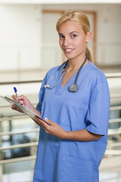 Blonde verpleegster schrijven op een Klembord — Stockfoto