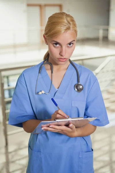 Seriöse Krankenschwester schreibt auf Klemmbrett — Stockfoto