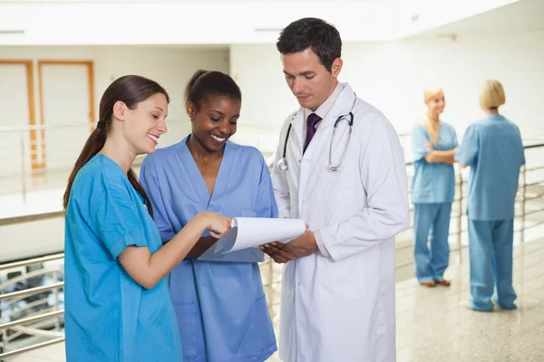 Doctor sosteniendo un portapapeles al lado de las enfermeras —  Fotos de Stock