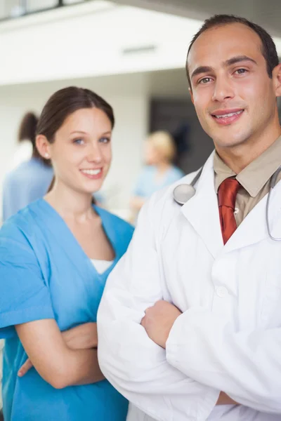 Médico y enfermera con los brazos cruzados — Foto de Stock