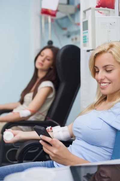 Patient receiving a transfusion using her mobile phone — Stock Photo, Image