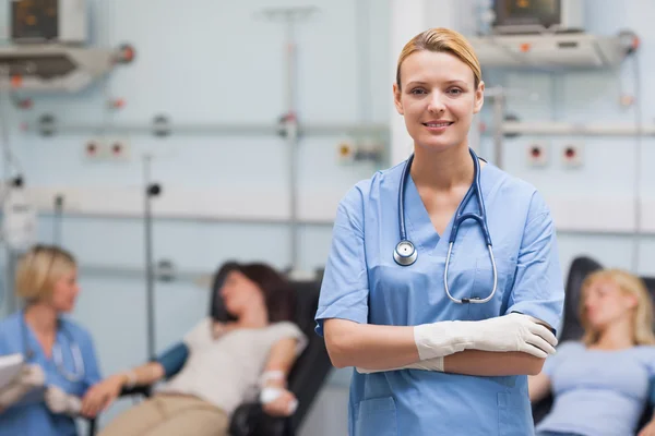 Медсестра, стоящая со скрещенными руками рядом с пациентами — стоковое фото