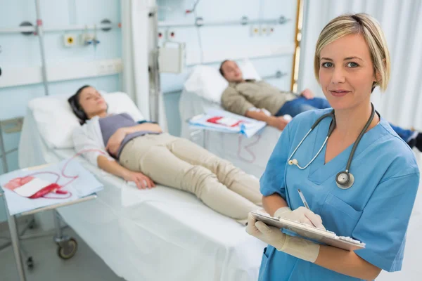 Nurse next to transfused patients writing on a clipboard — Stock Photo, Image