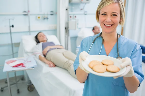 Nurse holding a plate of biscuits — Stock Photo, Image