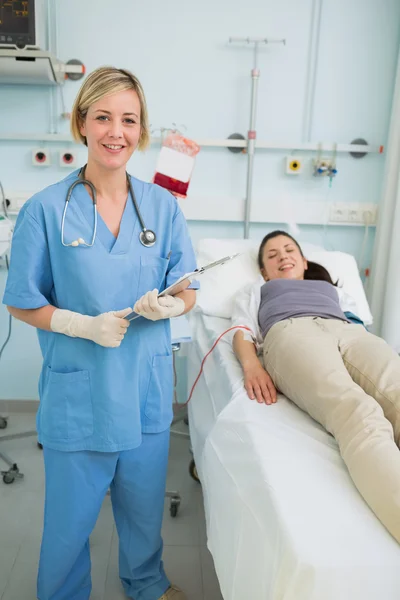 Nurse holding a clipboard while standing — Stock Photo, Image