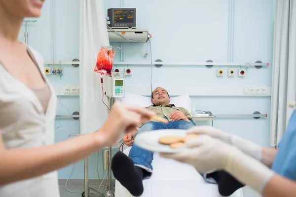 Infermiera che dà biscotti a un paziente — Foto Stock