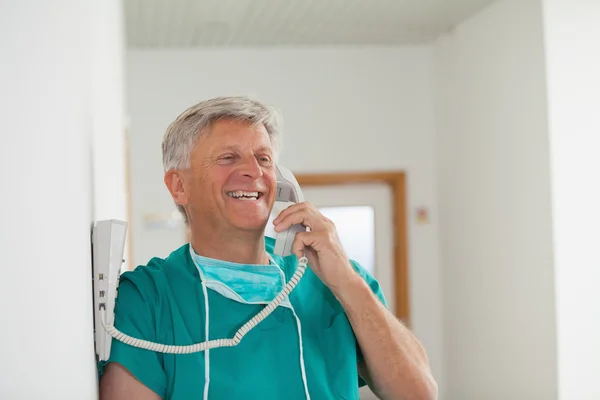 Chirurg uśmiechający się trzymając telefon — Zdjęcie stockowe