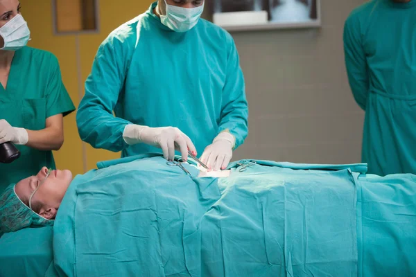 Surgeon opening the belly of a patient — Stock Photo, Image