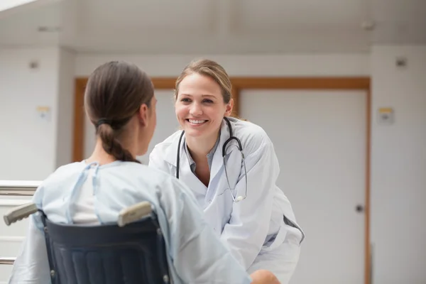 Leende läkare framför en patient på en rullstol — Stockfoto