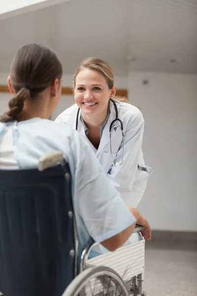 Médico olhando para uma paciente feminina em uma cadeira de rodas — Fotografia de Stock